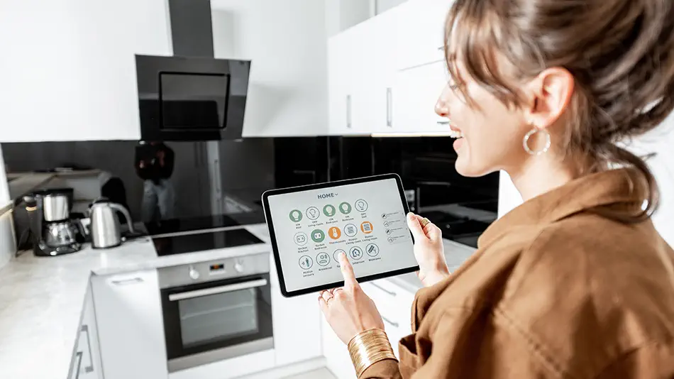 a woman controlling smart plugs using a tablet for kitchen appliances