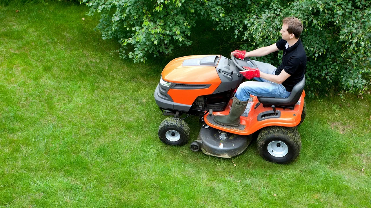 A ride-on lawn mower is being used to mow the lawn.