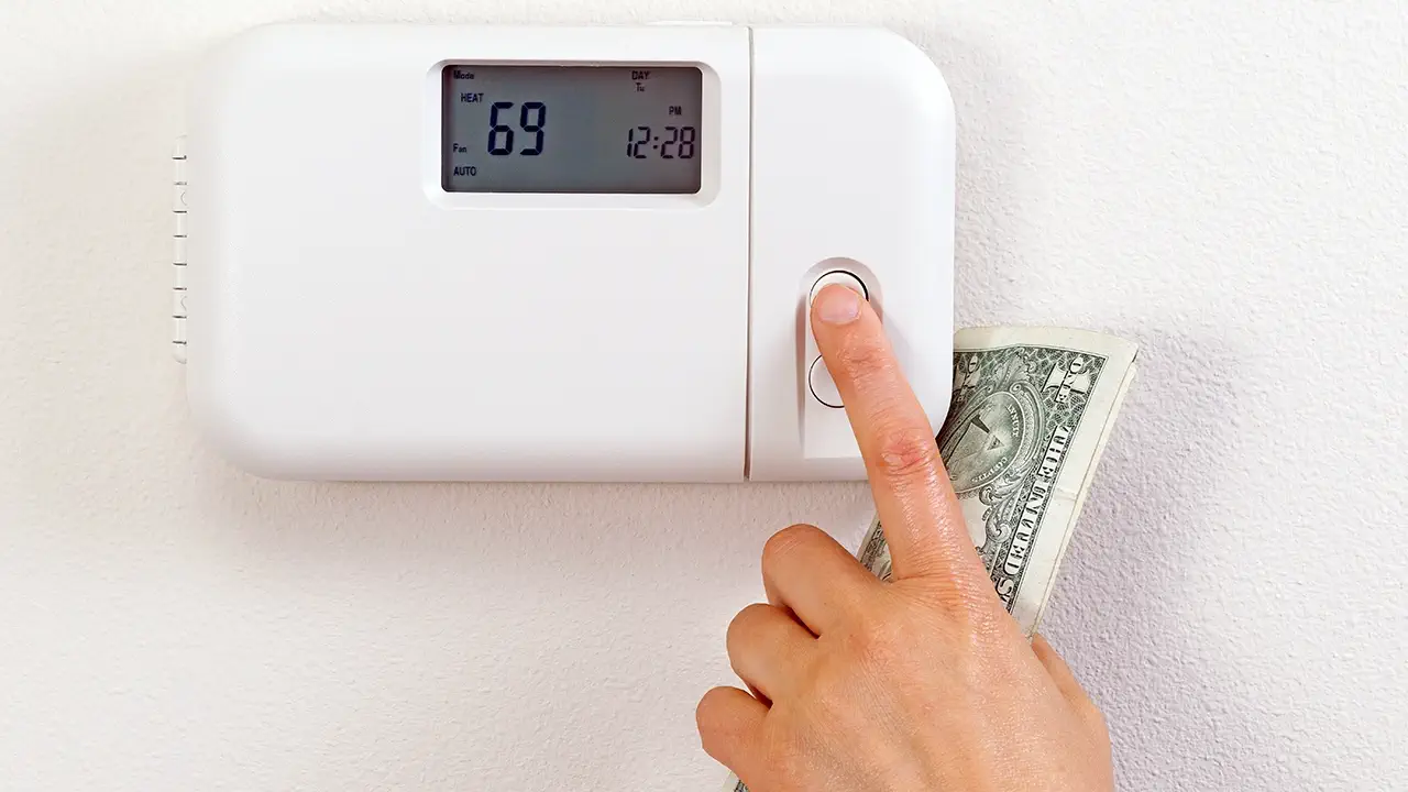 A smart thermostat is being operated with cash in hand.
